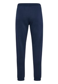 Pantaloni della tuta blu navy realizzati in morbido tessuto, con vita elasticizzata e orli a coste per una silhouette aderente. Nessuna tasca visibile.