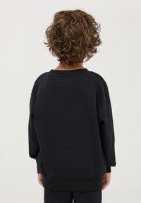 Felpa in cotone nera con vestibilità rilassata, collo a girocostato e maniche lunghe. La vista posteriore non presenta ulteriori motivi o decorazioni.