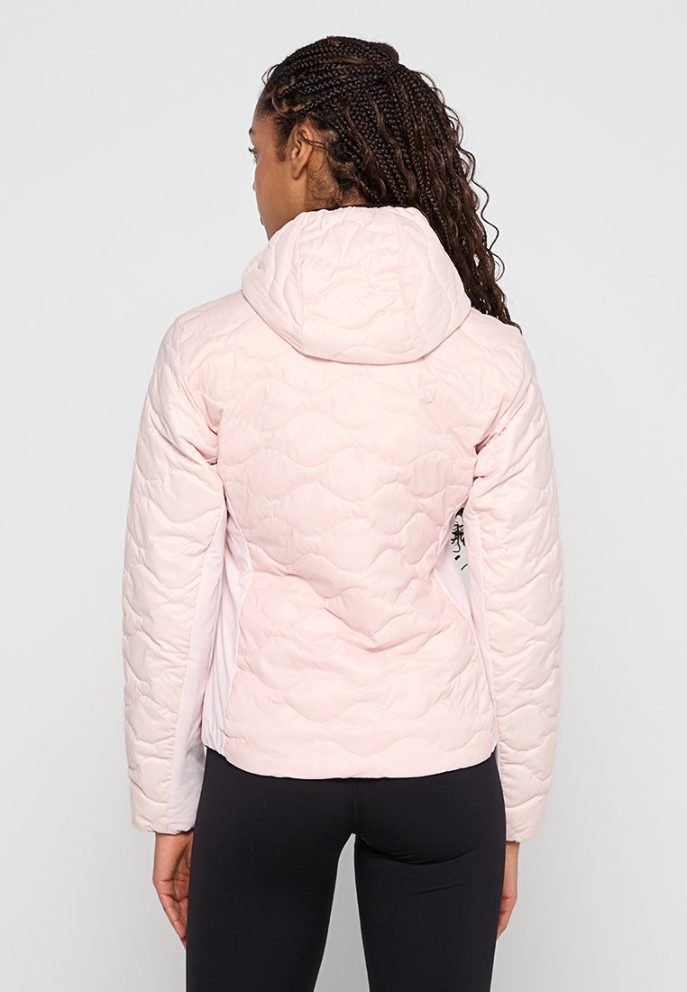 Giacca imbottita rosa con cappuccio, caratterizzata da una texture liscia e motivi a coste, abbinata a leggings neri per un look a contrasto.