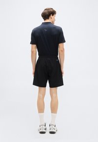 Μπλουζάκι πόλο ναυτικού στυλ με κοντά μανίκια, σορτς με μαύρη ελαστική μέση και λευκές κάλτσες μέχρι τον αστράγαλο. Σχεδιασμένο για άνεση και εφαρμογή, με ελάχιστη ορατή εμπορική σήμανση.