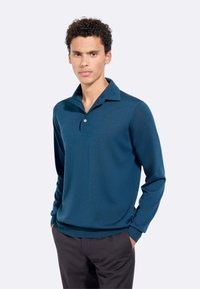 Polo shirt a maniche lunghe di colore blu navy con collo a risvolto e chiusura a bottoni, realizzato in tessuto morbido con design aderente.