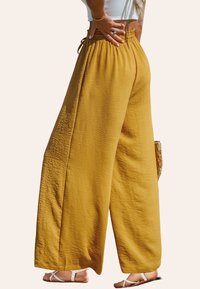 Wijde broek in mosterdgeel, gemaakt van textuurstof, met een geraffineerde elastische tailleband en een verstelbaar trekkoord.