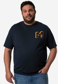 Námořnická modrá pánská košile s krátkým rukávem vyrobená z měkké tkaniny, s oranžovým grafickým logem "M" na levé hrudi. Uvolněný střih a kulatý výstřih.