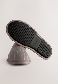 Chaussons en tissu gris avec un motif à rayures, forme arrondie, semelle en caoutchouc et détails couturés. Doublure intérieure douce. Taille indiquée sur la semelle.