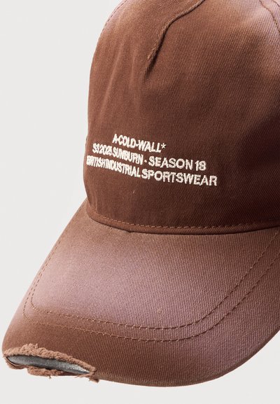 Καφέ καπέλο μπέιζμπολ με φθαρμένη άκρη και λευκό κεντημένο κείμενο που γράφει "A-COLD-WALL* SS20& SUNBURN - SEASON 18 BRITISH INDUSTRIAL SPORTSWEAR".