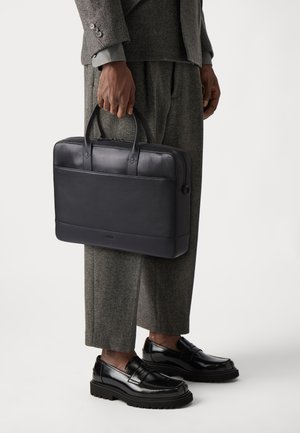 Svart skinnportefølje med doble håndtak, glatt finish og enkel design. Har en frontlomme og glidelås.