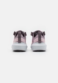Zapatillas rosas y grises con un upper texturizado, talón reforzado y una suela gruesa de color gris claro moteado; cuenta con tiradores en la parte posterior.