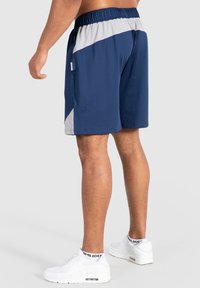 Pantalones cortos deportivos de color azul marino con un patrón diagonal gris claro, cintura elástica y bolsillos laterales, fabricados con un tejido ligero.