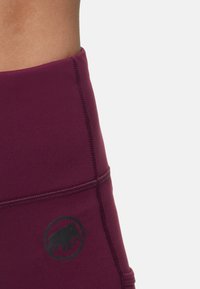 Mörkröda högmidjade träningsleggings med sydda detaljer och en svart elefantlogotyp. Tillverkade av elastisk och slät tyg.