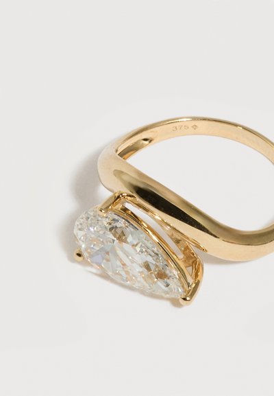 Anillo de oro con una gran piedra preciosa clara en forma de pera colocada horizontalmente, marcado con "375" en el interior de la banda.