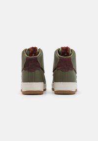 Green high-top sneakers featuring a textured dark red suede accent at the heel, white midsole, and gum rubber outsole.