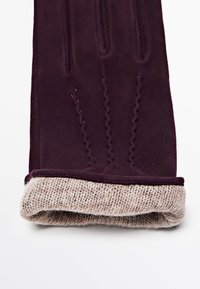 Guanti bordeaux con un polsino a maglia morbida, caratterizzati da dettagli testurizzati e una finitura in tessuto liscia. Il polsino è di un beige chiaro con un motivo intrecciato.