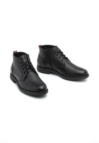 Botas de cuero negro hasta el tobillo con acabado texturizado, puntera redonda, cordones en la parte delantera y cremallera lateral. La suela de goma ofrece tracción y durabilidad.