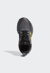 Black athletic shoe with yellow accents, mesh upper, textured sole, and black laces. Features a reinforced heel and logo tag on the tongue.