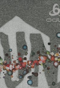 Šedá látková košile s velkým bílým grafickým prvkem a barevným rozstřikem s červenými, modrými a zelenými akcenty. Text se objevuje v rohu.