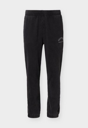 Pantaloni de trening negri cu talie și manșete elastice, având un logo "Champion Training Club" pe coapsa stângă superioară.
