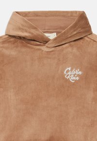 Hoodie en velours côtelé marron avec un logo "Calvin Klein" brodé en blanc, doté d'un tissu texturé et d'un design de col plié.