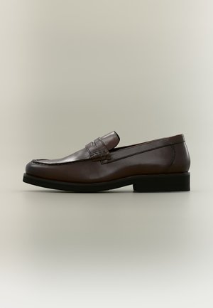 Mocassin homme en cuir marron foncé avec semelle noire et détail classique de bride penny, présenté de profil sur fond neutre.