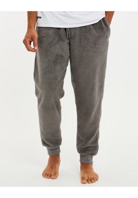 Pantalons de survêtement en polaire gris avec taille élastique et poignets. Texture douce, coupe droite et poches latérales. Sans motifs ni logos visibles.