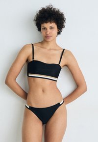 Μαύρο μπικίνι σετ με μπαντεού τοπ με λεπτές ρίγες και διακοσμητική ρίγα σε χρυσό, άσπρο και μαύρο χρώμα. Κλασικό μοντέλο κάτω μέρους.