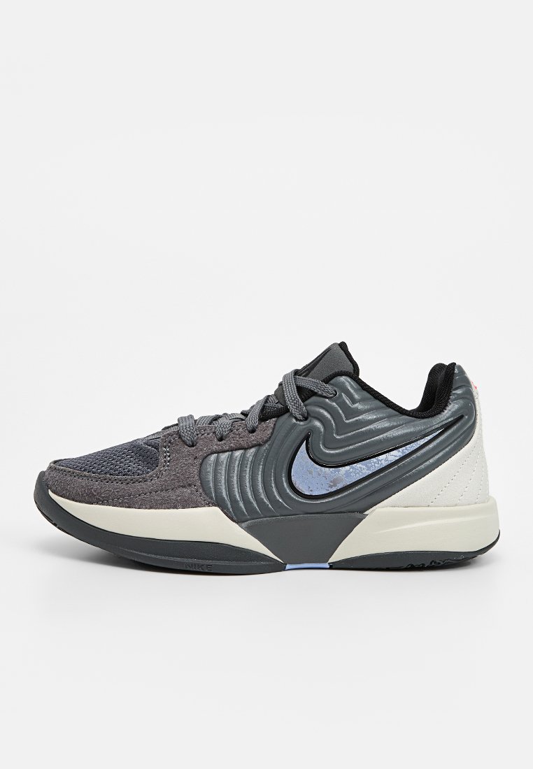 Vista lateral de una zapatilla Nike en gris y negro con parte superior texturizada, suela de color beige claro y logo de swoosh reflectante en azul.