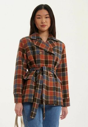 Veste en mélange de laine à carreaux avec des teintes de marron, bleu et orange. Présente un design croisé, une taille ceinturée et de grands revers.