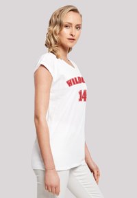 Balta trumpa rankovėmis T-shirt marškinėliai su raudonu užrašu "WILD" ir numeriu "14" žemiau, su laisvu siluetu ir V formos iškirpte.