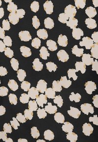 Czarna tkanina z nieregularnymi białymi i beżowymi plamami, tworząca wzór o zróżnicowanych kształtach i fakturach.