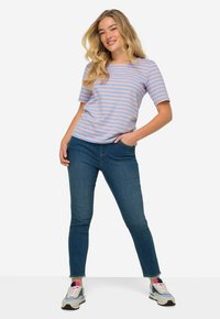 Camisa de manga corta a rayas en azul pastel y rosa; combinada con jeans azul oscuro y zapatillas grises con acentos multicolores.