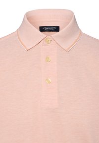 Hellrosa Poloshirt aus strukturiertem Stoff mit klassischem Kragen, drei goldenen Knöpfen und kontrastierenden weißen Akzenten am Kragen.