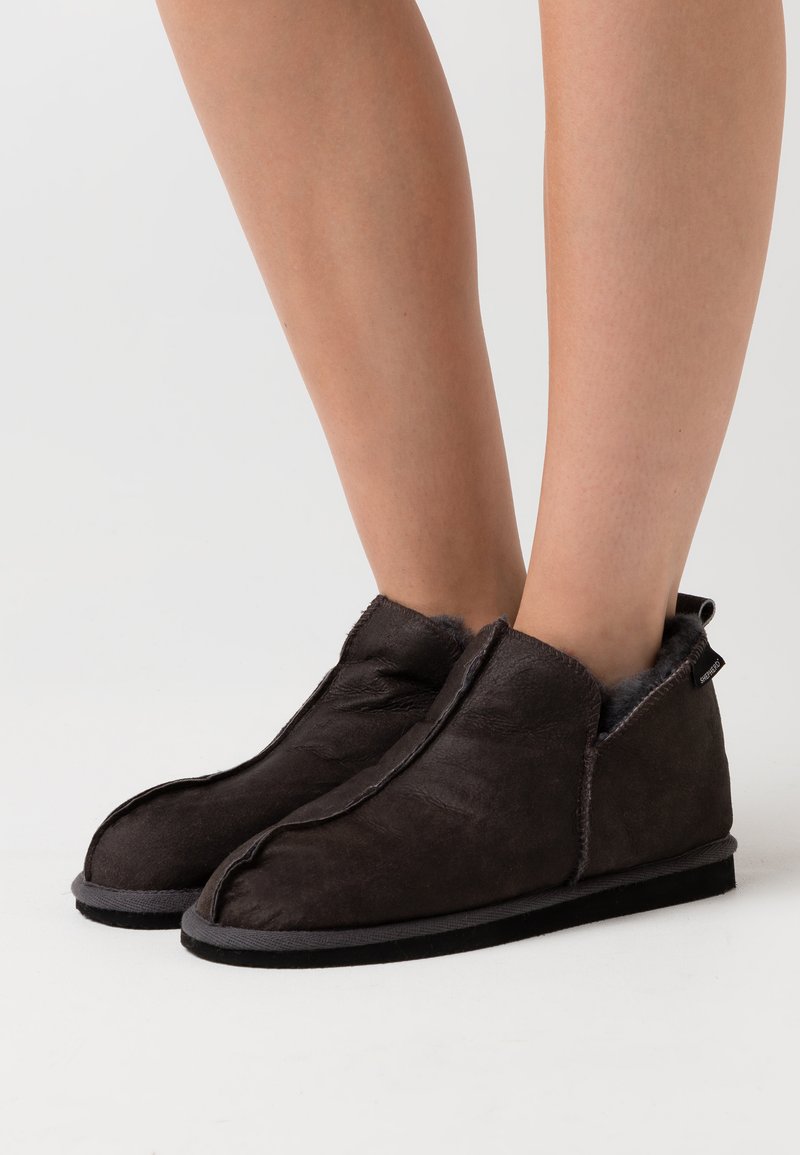 Donkerbruine enkellaarzen van zacht suède, met een gestikt randje, een grijze voering en een platte zool met een subtiele hak.