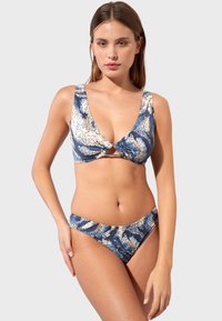 Zestaw bikini w kolorze niebieskim i beżowym z kwiecistym wzorem fal. Górna część ma głęboki dekolt w kształcie litery V i związany środek, a do zestawu pasują niskie majtki.