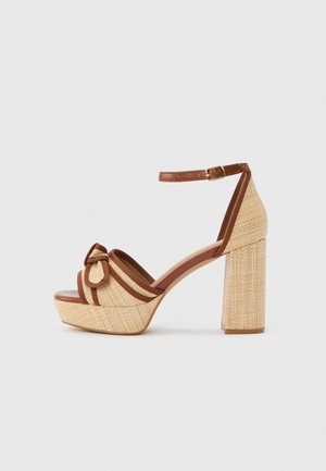 Sandalia de plataforma tejida beige con tacón grueso de bloque, borde marrón, correa al tobillo con hebilla y lazo decorativo en la correa frontal.