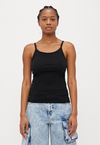 Svart, tettsittende tank topp med tynne stropper, laget av glatt stoff; har en rund hals og minimalistisk design uten mønstre eller utsmykninger.