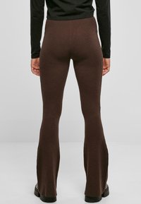 Csíkozott, barna szélesített leggings, illeszkedő derékkal és textúrált felülettel, fekete, hosszú ujjú toppal párosítva. Egyszerű és letisztult dizájn.