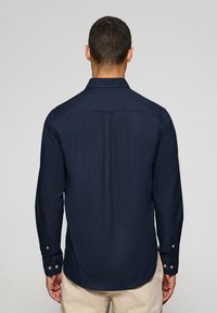 Mörkblå långärmad skjorta med button-down-krage, strukturerad tyg och manschetter med knapp, med en ryggdel och diskret lyster.