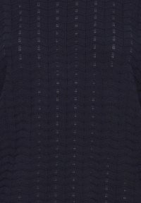 Tissu bleu marine foncé avec un motif zigzag vertical et de petits trous œillets régulièrement espacés sur l’ensemble du textile tricoté.