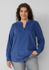 Langärmliges blaues Hemd mit V-Ausschnitt, weichem Material und lockerer Passform. Verfügt über einen dezenten Saum und subtile Nähte.