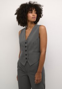 Gilet sans manches gris avec un col en V, featuring cinq boutons noirs et deux poches avant ; coupe ajustée avec un léger éclat et une texture lisse.