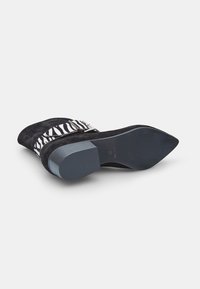 Must mustaga nahkking, millel on tigu mustri aktsent, ruudukujuline varvas ja madal ploki konts. Tallal on sile ja lame pind koos kerge kõverusega.