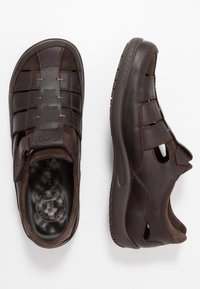Braune Leder-Sandalen mit geschlossener Zehe, verstellbarem Riemen, Belüftungsschlitzen, strukturiertem Sohlen und dekorativer Naht.
