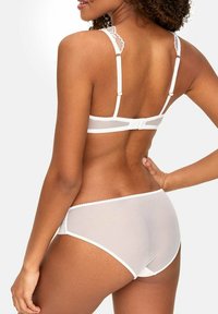 Biały zestaw bielizny składający się z przezroczystego biustonosza z falbaniastymi koronkowymi ramiączkami oraz dopasowanych hipsterów, podkreślający delikatne wykończenia i miękką teksturę.