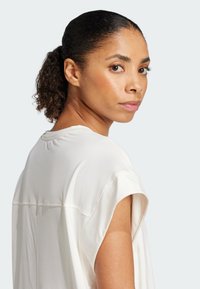 Zijdeachtige, crèmekleurige blouse met korte, losse mouwen en een ronde halslijn, met subtiele stikdetails op de achterkant.