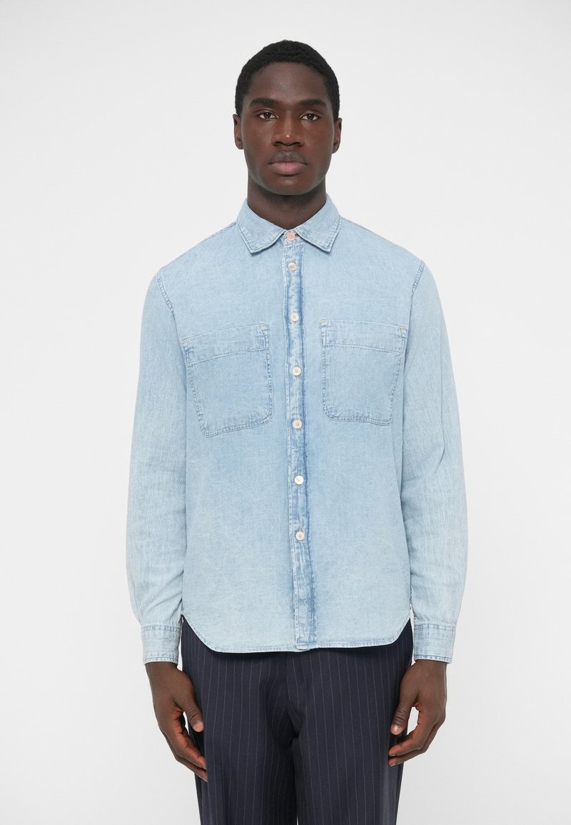 Hellblaues Denimhemd mit langen Ärmeln, durchgehendem Knopfverschluss, zwei Brusttaschen und klassischem Kragen. Glatte Textur und entspannte Passform.