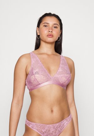 Bralette de renda rosa com decote em V profundo, bordas recortadas e faixa de cetim. Apresenta padrões florais e um fio dental de renda combinando.