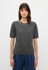 Tmavě šedé tričko s krátkým rukávem a kulatým výstřihem, zdobené několika bílými korálky kolem límce. Měkká, texturovaná tkanina.