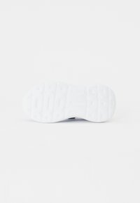 Semelle de sneaker blanche avec un motif en caoutchouc texturé, présentant des rainures définies et des éléments d'amortissement pour une traction et un soutien.