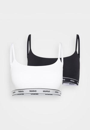 Deux bralettes, une blanche et une noire, en tissu lisse. Les deux présentent de fines bretelles et une bande logo de couleurs contrastées.