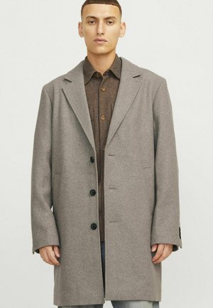 Abrigo de lana gris con solapas muestradas, diseño de un solo pecho, dos bolsillos frontales y botones negros, llevado sobre una camisa marrón de botones.