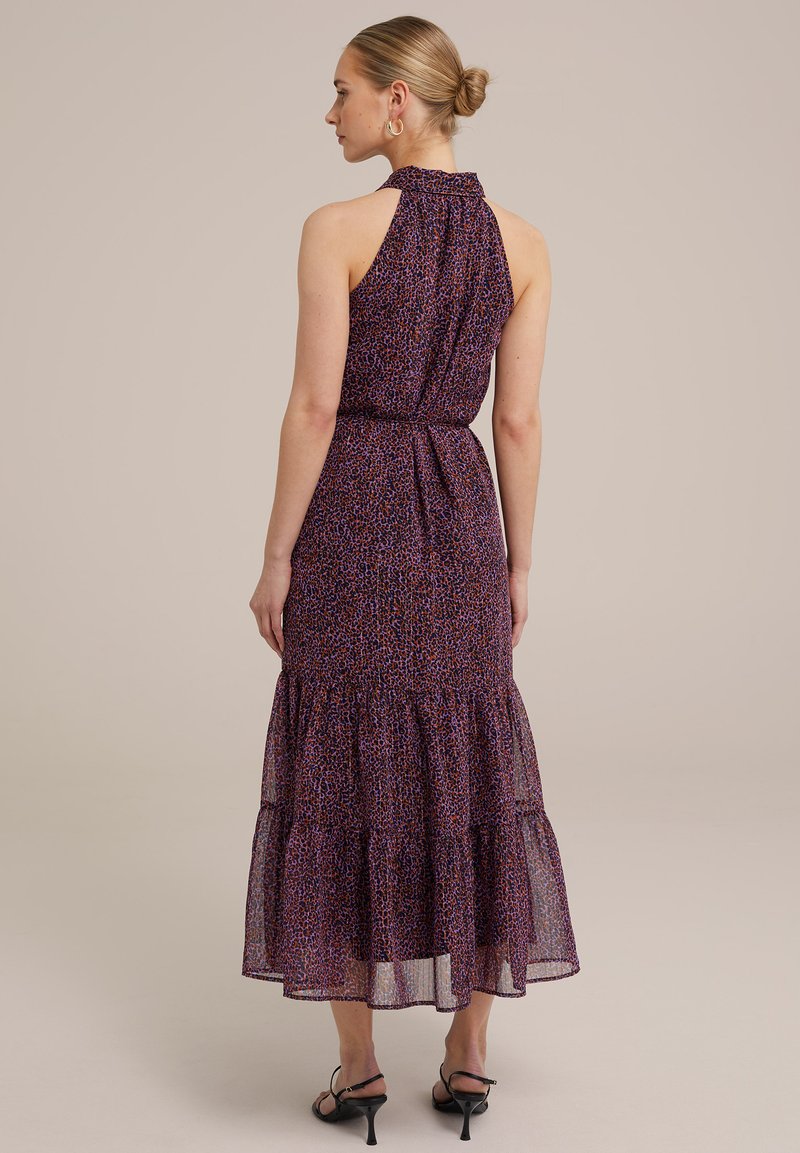 Lila, gemustertes, ärmelloses Maxikleid mit einem Rüschensaum, einer taillierten Passform und einem hohen Ausschnitt. Tragen mit schwarzen, schmalen Absätzen.